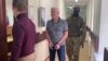 Robert Shonov, a former worker at the now-closed U.S. Consulate in Vladivostok, is led away by Russian security personnel in May.