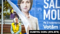 An woman sits on a street bench in downtown Chisinau behind a campaign tent for President Maia Sandu on October 31.