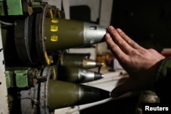 Un soldat ucrainean arată obuze de 155 mm în interiorul unui obuzier autopropulsat în apropierea orașului Bahmut de pe linia frontului.