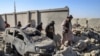 Taliban security personnel walk past a damaged car in Kandahar province on October 16,.