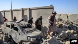 Taliban security personnel walk past a damaged car in Kandahar province on October 16,.