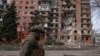 Украински военен е заснет пред разрушена от руските военни жилищна сграда в град Покровск.