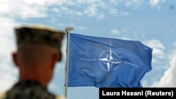 Një ushtar i KFOR-it para flamurit të NATO-s. Fotografi nga arkivi.